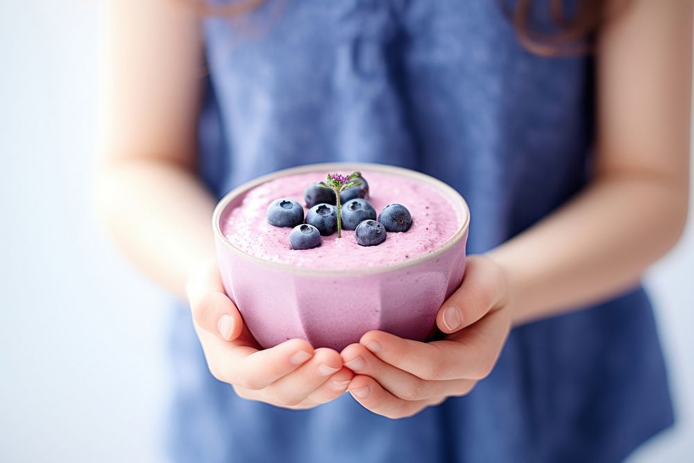 Girl holding blueberry smoothie bowl dessert fruit plant.