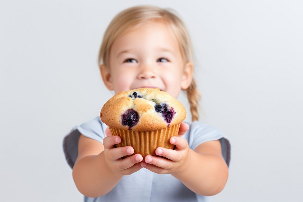Small girl holding blueberry muffin dessert cupcake food.