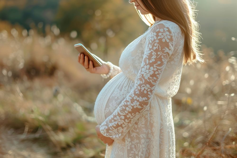 Pregnant woman checking adult dress phone.
