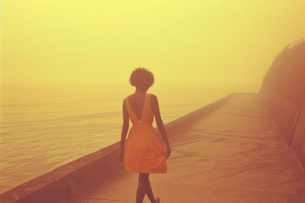 African woman walking on walkpath by sea architecture backlighting tranquility.