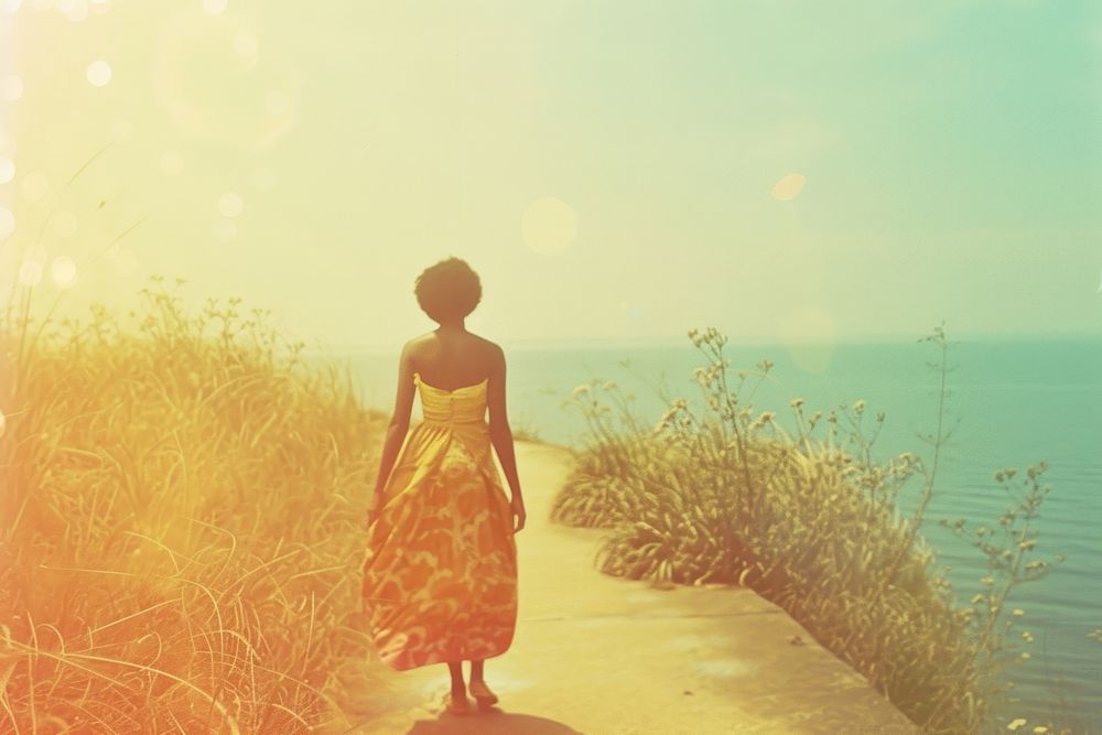 African woman walking on walkpath by sea standing outdoors horizon.