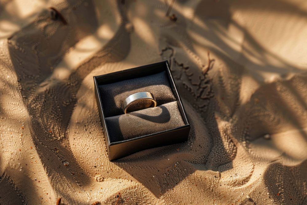 Wedding ring in box on sand jewelry celebration accessories.
