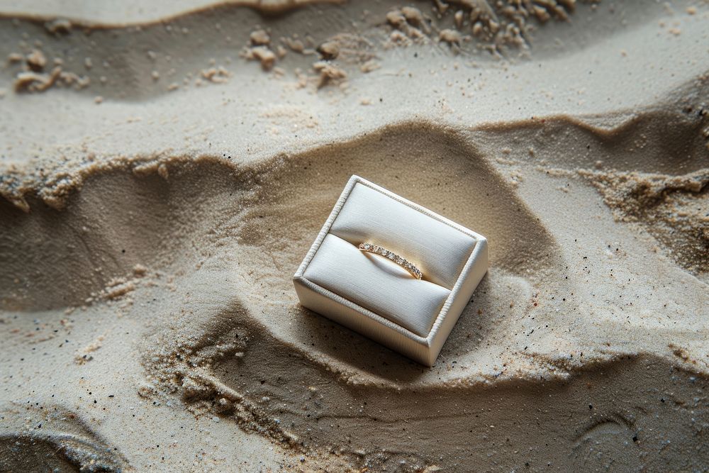 Wedding ring in box on sand jewelry text accessories.