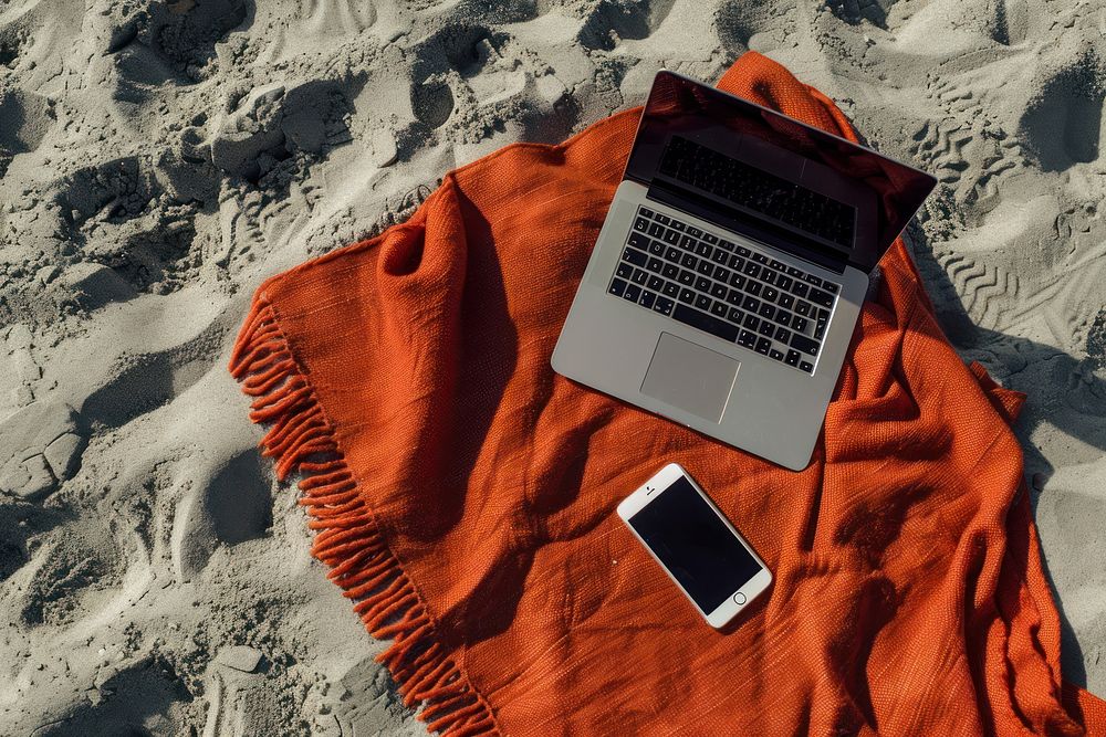 Beach blanket with laptop and mobile phone on sand computer outdoors portability.