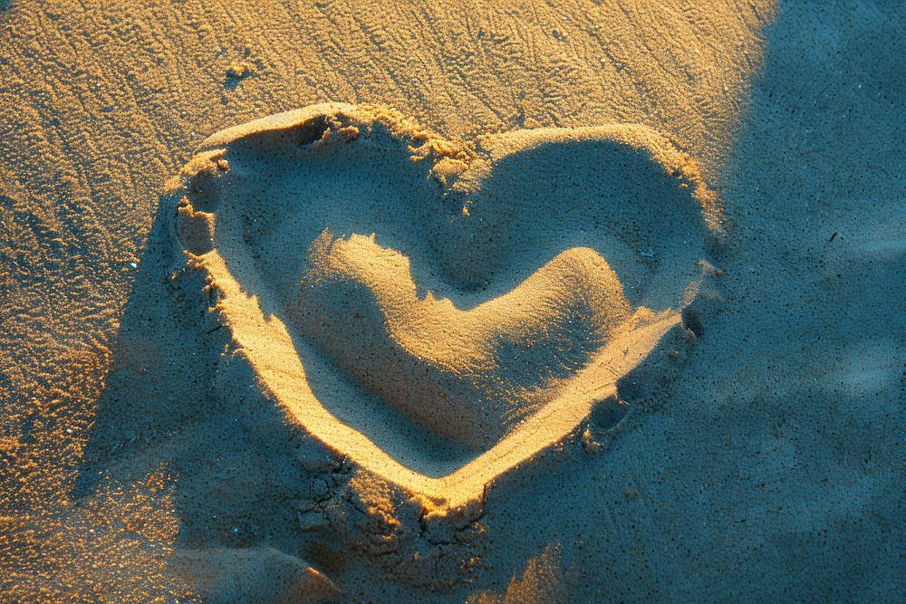 Shadow Hand Making Heart on sand backgrounds outdoors nature.