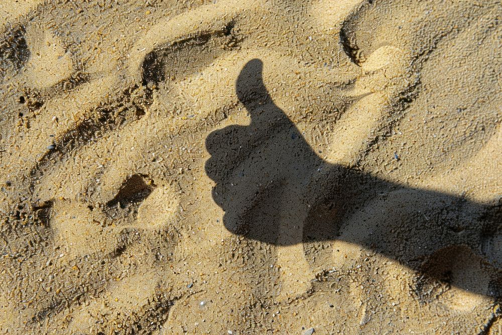 Shadow thumbs up hand on sand backgrounds footprint outdoors.