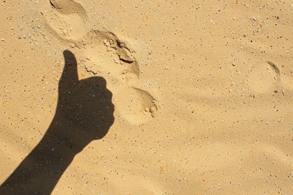 Shadow thumbs up hand on sand backgrounds footprint outdoors.