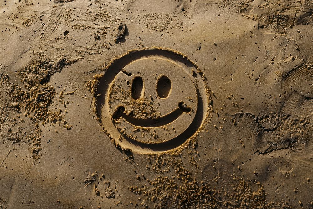 Smile icon drawing on sand backgrounds outdoors text.