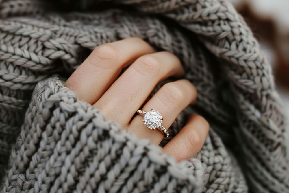Diamond ring on woman finger engagement jewelry sweater.