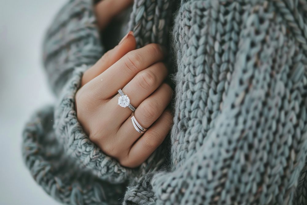 Diamond ring on woman finger sweater engagement jewelry.