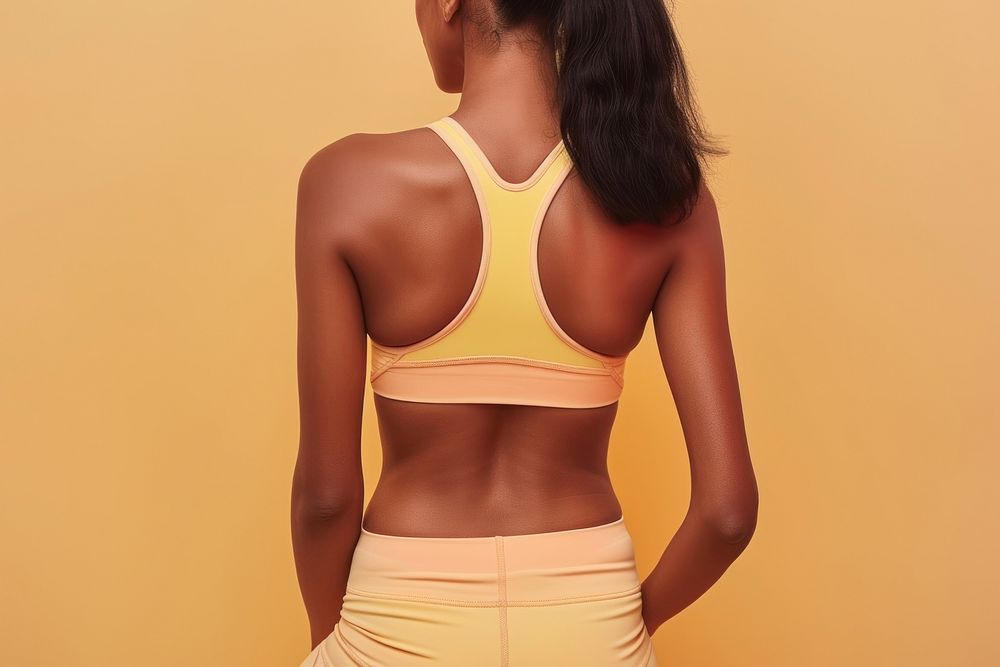 Woman back wearing yoga outfit yellow adult undergarment.