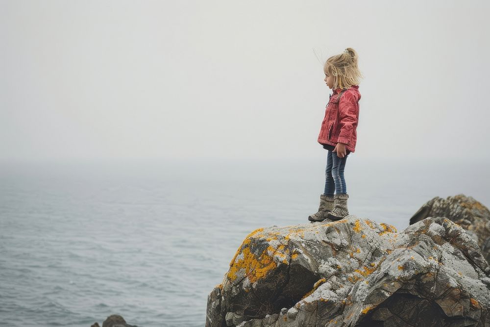 Little girl on the sea rock standing outdoors.