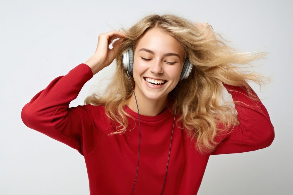 Young woman blond long hair dancing happy and cheerful headphones sweater smiling.