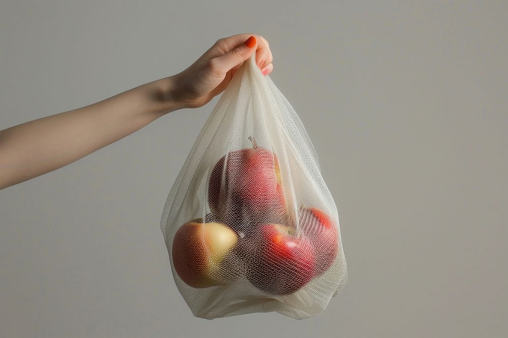 Hand holding mesh bag fruit plastic apple.