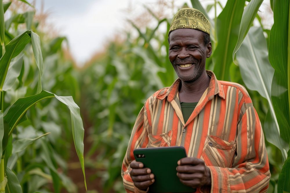 Farmer stands in front of his corn field holding a tablet computer adult happy.