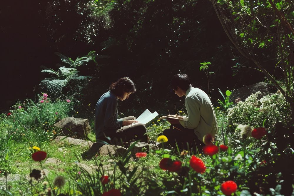 Man and woman taking notes in the garden outdoors woodland reading.