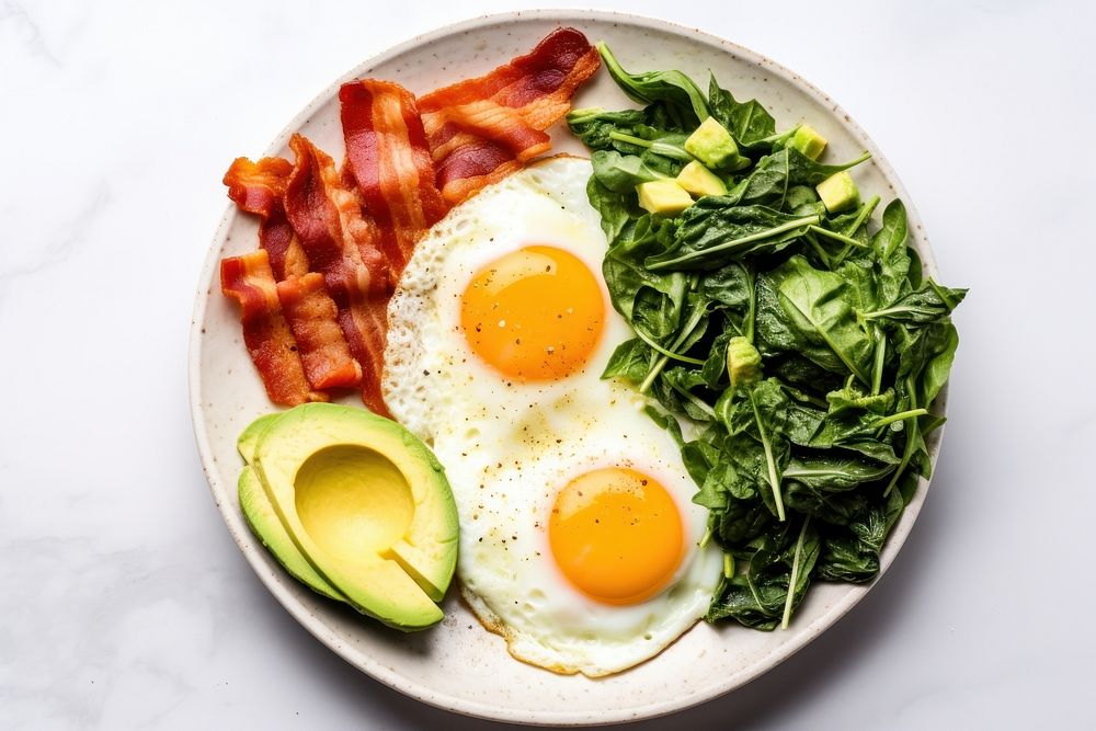 Keto friendly low carb breakfast plate with sunny side up eggs spinach avocado bacon.