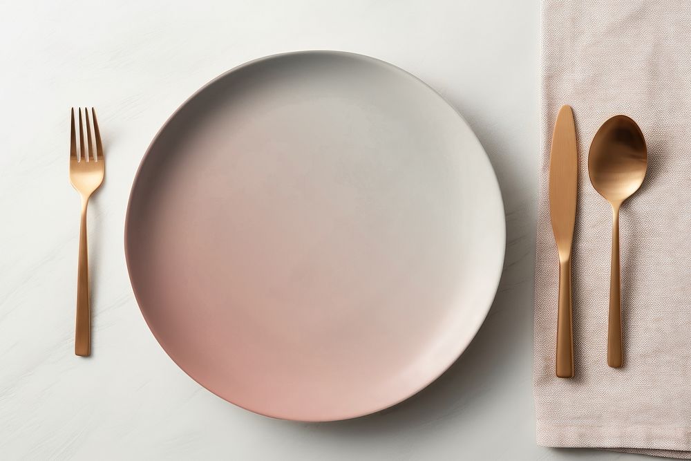 Brass cutlery by gradient pink plate flat lay