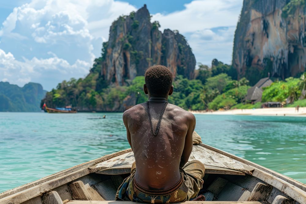 African man sitting in front of a boat back vehicle day.