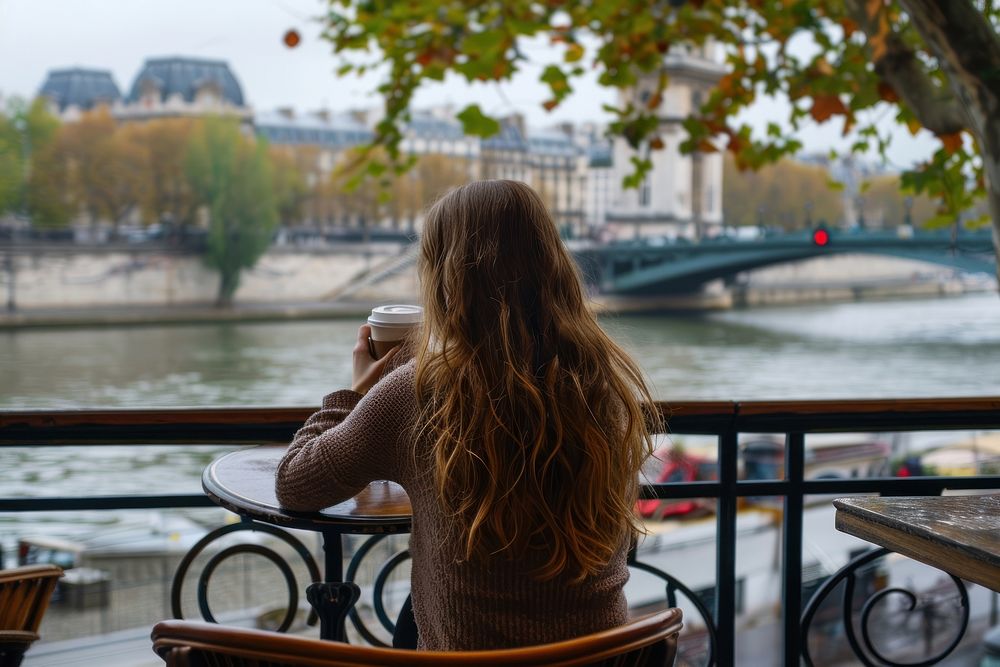 Woman drinking a coffee at a table outdoors portrait sitting.