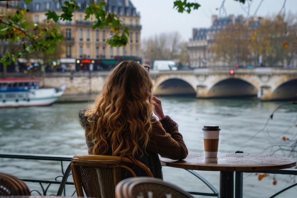 Woman drinking a coffee at a table outdoors sitting chair.