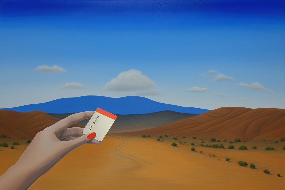 Hand holding credit card outdoors desert nature.