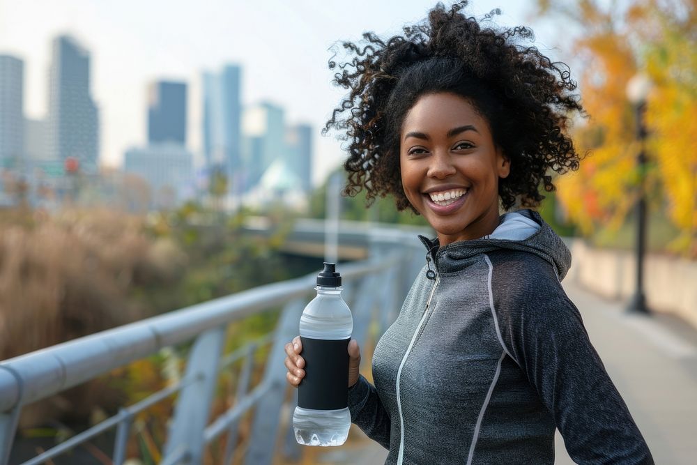 Happy african american female runner holding reusable water bottle smile photo city.