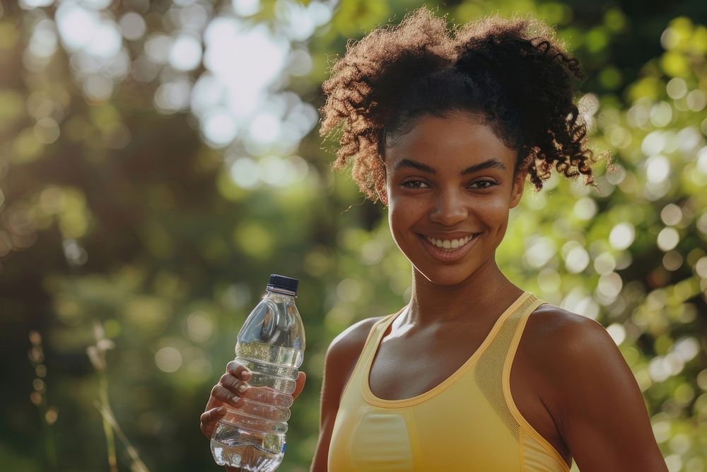 Happy african american female runner holding water bottle smile adult refreshment.