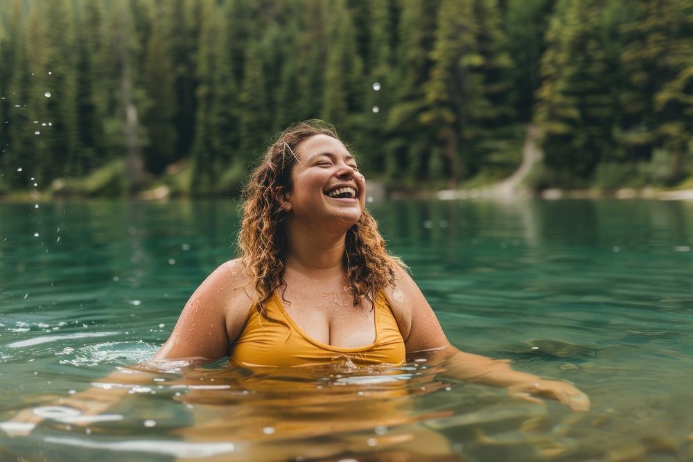 Happy chubby woman standing in water laughing outdoors bathing.