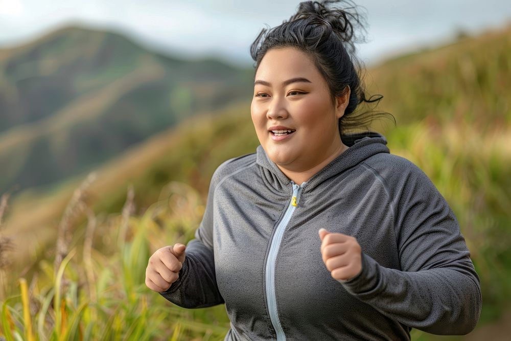 Happy chubby asian woman jogging at the mountain running head exercising.