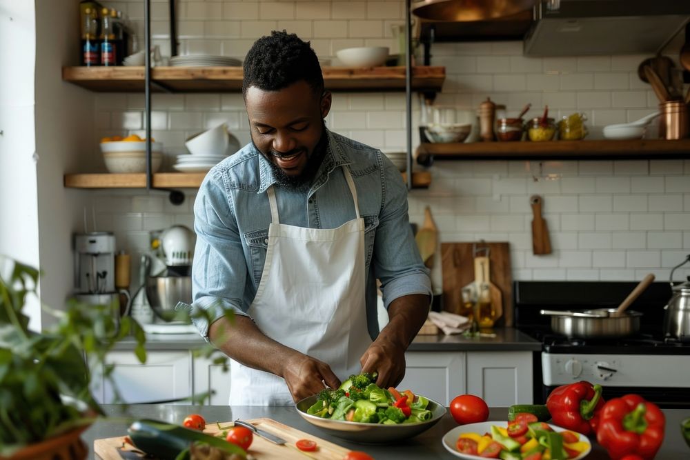 An african american man prepare salad in a kitchen cooking adult chef.