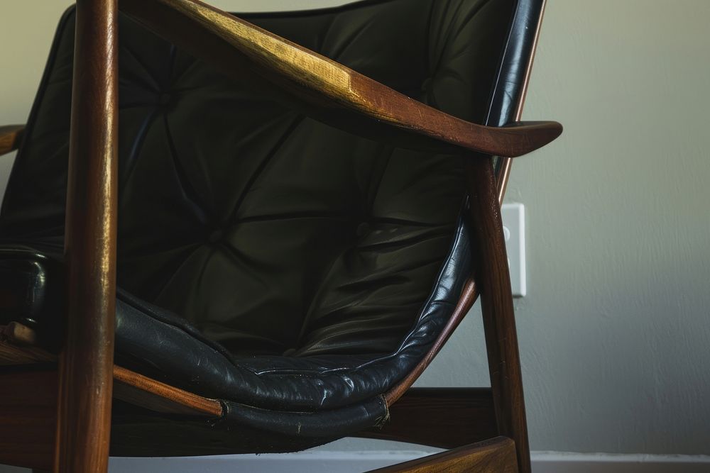 A midcentury wooden chair with black leather furniture armchair armrest.
