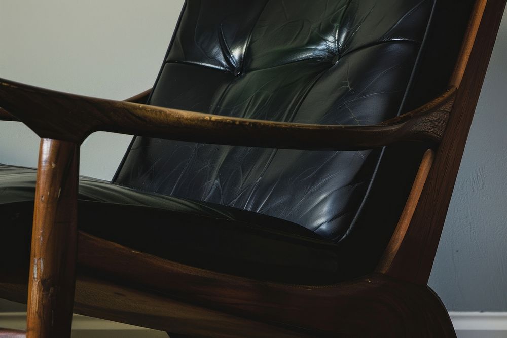 A midcentury wooden chair with black leather furniture armchair armrest.