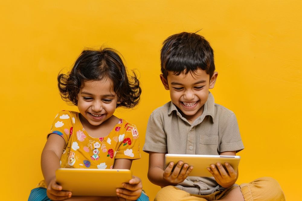 2 Indian kids reading the tablet happy person female.