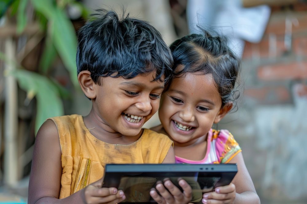 2 south asian kids reading the tablet photo happy electronics.