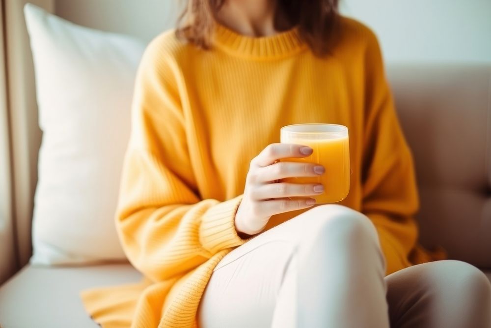 Woman holding a cup of orange juice sitting sweater drink.