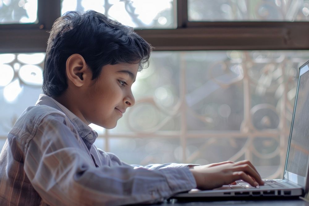 South Asian young boy using laptop electronics executive computer.