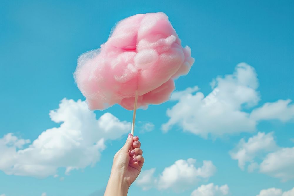 The hand of women holding pink cotton candy in the background of the blue sky confectionery outdoors sweets.
