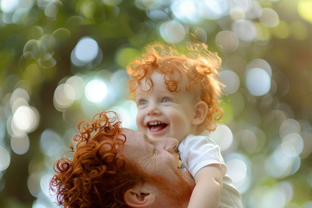 Red hair kid playing with father in the park laughing portrait outdoors.