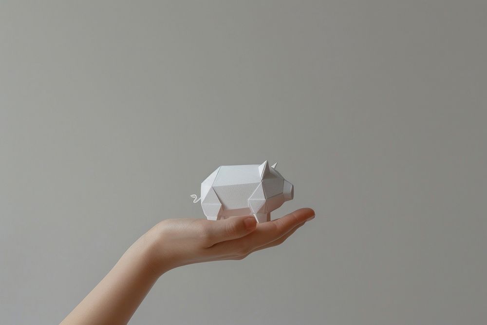 A piggy bank paper cut model origami holding hand.