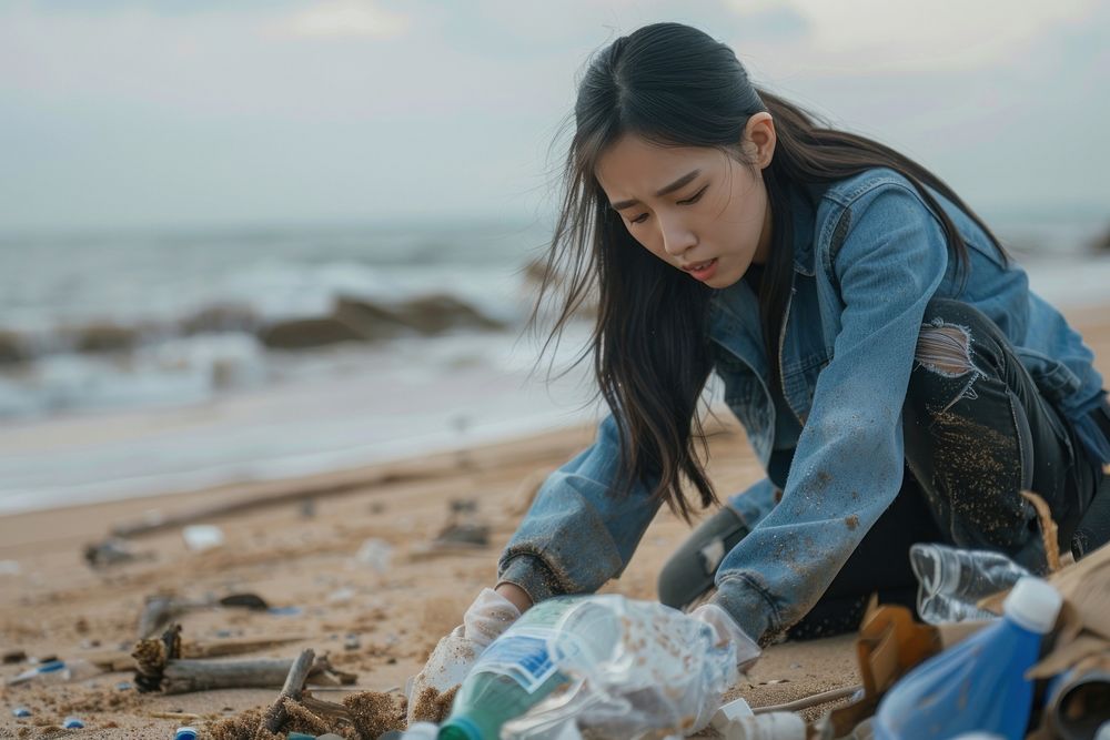 Asian woman volunteering garbage beach shoreline.