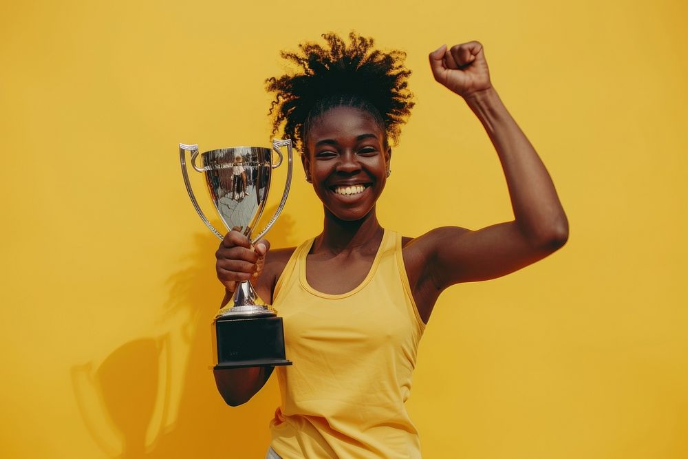 Photo of an black athlete woman raising a gold trophy triumphant person human.