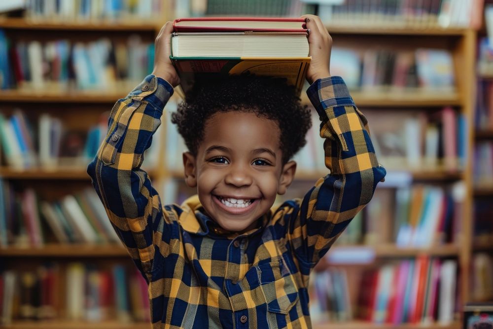 Black child lifts a book and places it on his head library publication student.