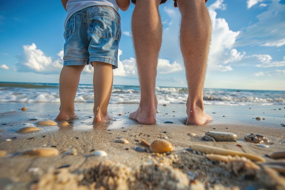 Dad and son standing on beach barefoot outdoors nature.