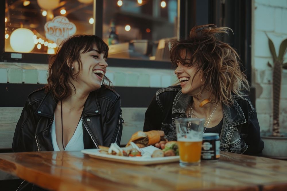 Two happy female having meal and beer and laughing table adult food.