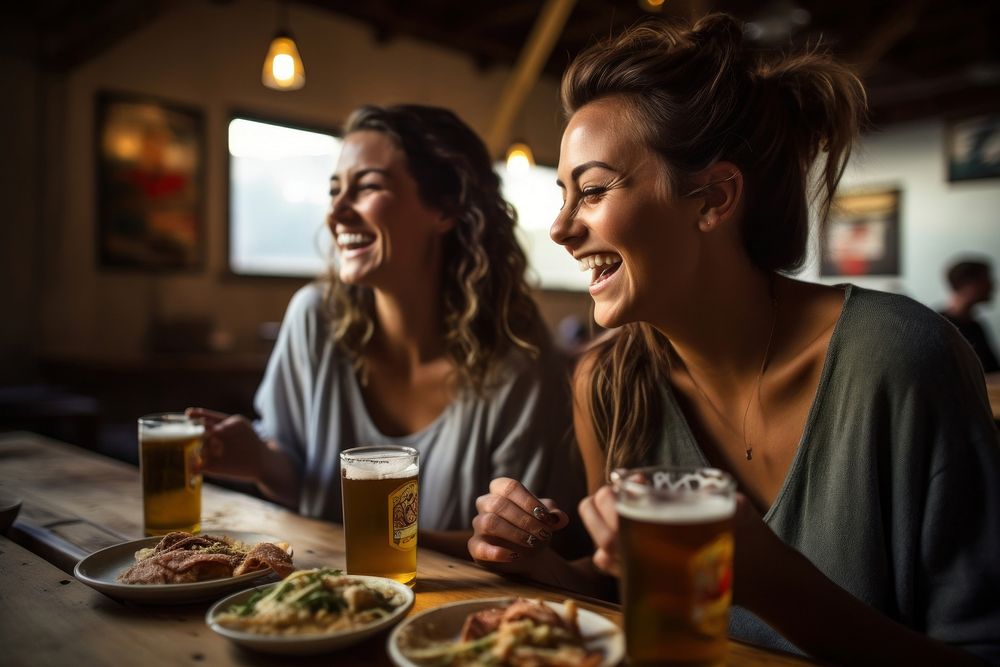 Two happy female having meal and beer and laughing drink smile glass.