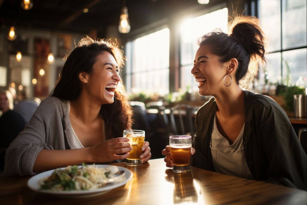 Two happy female having meal and beer and laughing drink food togetherness.