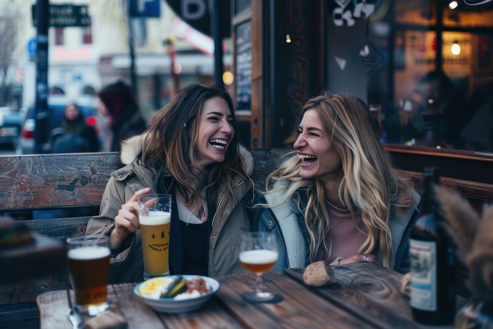 Two happy female having meal and beer and laughing drink adult fun.