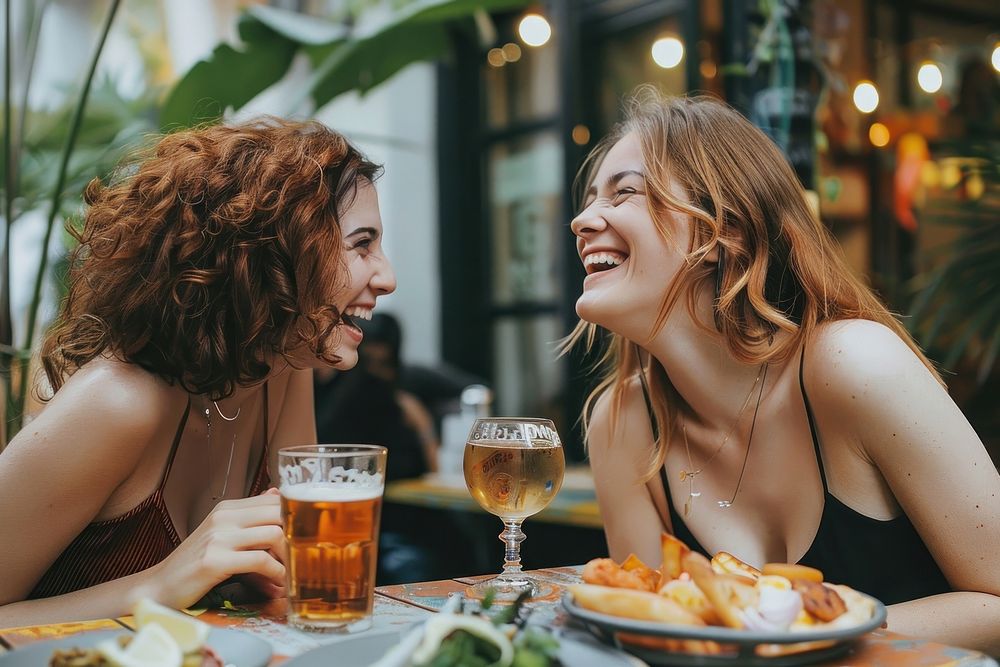 Two happy female having meal and beer and laughing drink party adult.