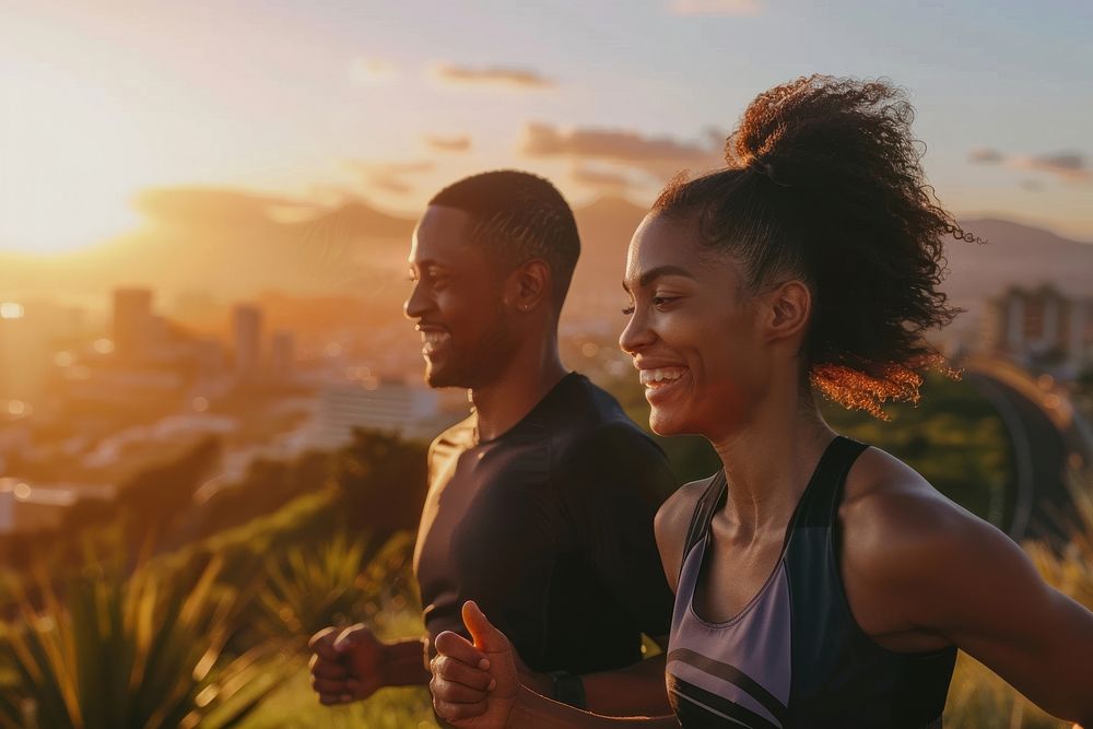 Fit young couple smiling while out for a run together along the road at sunset running adult togetherness.